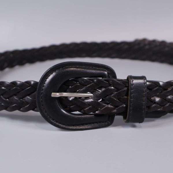 Närbild på bältets metallspänne och flätad struktur