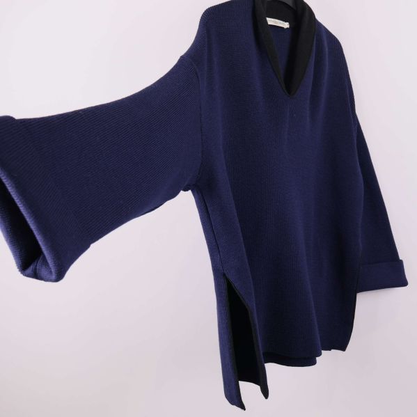 Ärm och sidovy på blå stickad tröja med djupa sidslitsar