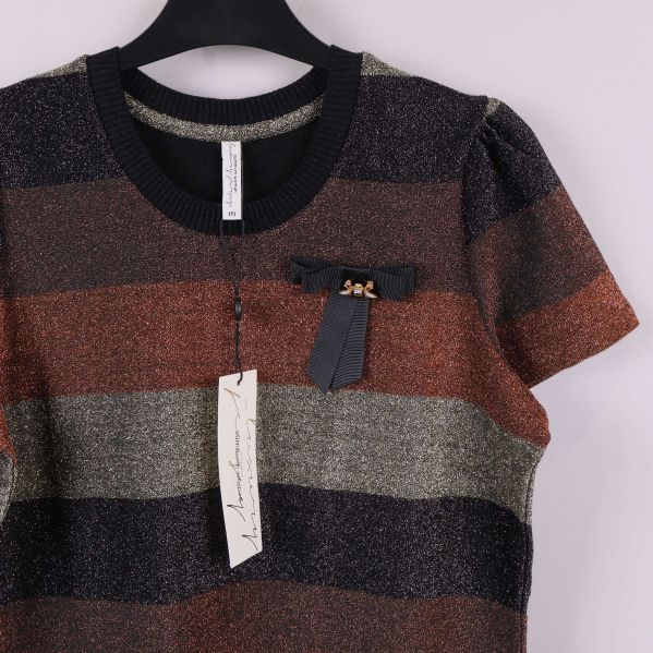 Dekorativ rosett och brosch framtill på t-shirt