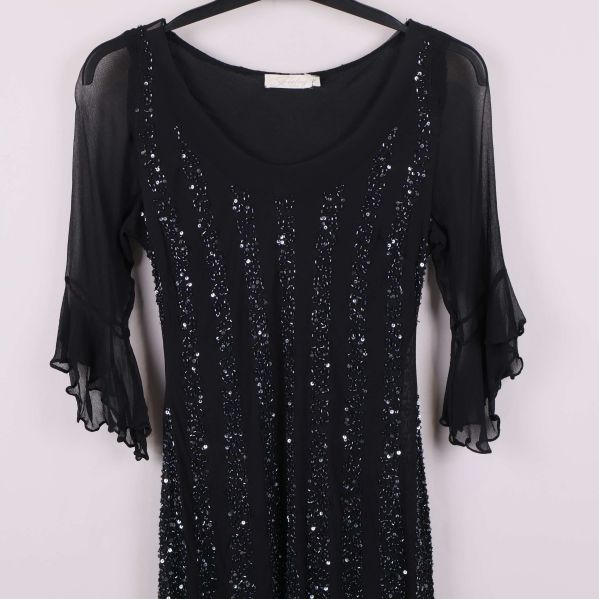 Halvbild på klänningens ovandel och ärmar med paljetter