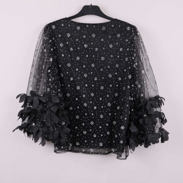 Baksida av svart topp med paljettmönster och bladapplikationer