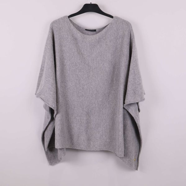 Ljusgrå poncho hängande på svart galge framifrån