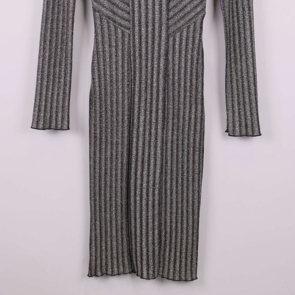 Nederdel av långärmad glittrig stickad klänning visas framifrån