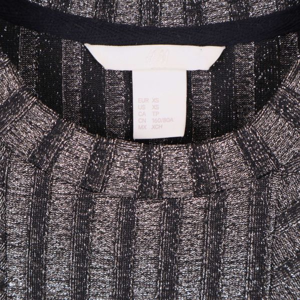 Närbild på hals och storleksetikett XS på ribbstickad klänning