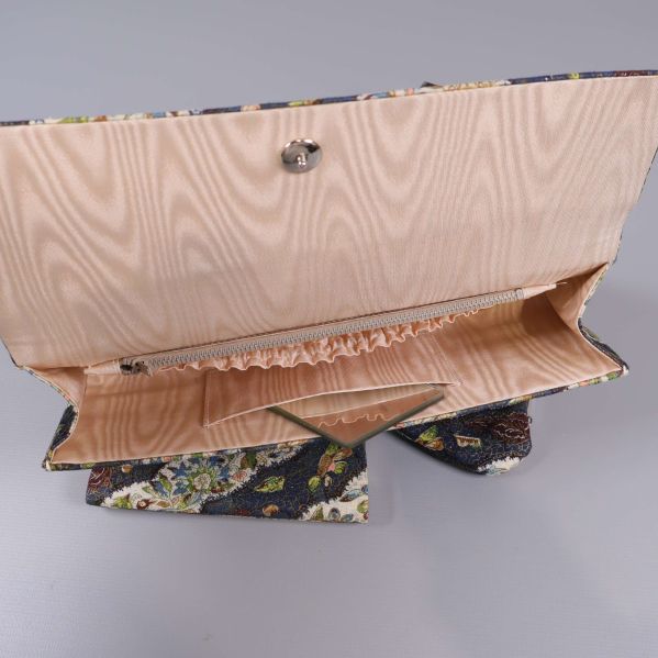 Öppen clutch med ljusfärgad insida och dragkedja