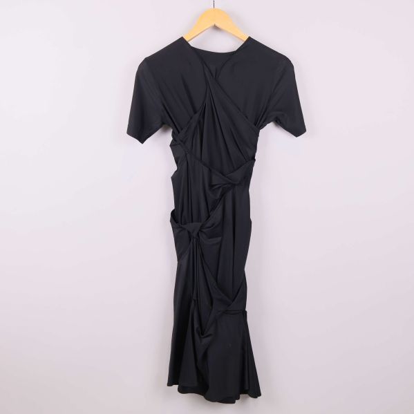 Baksida av svart draperad klänning 