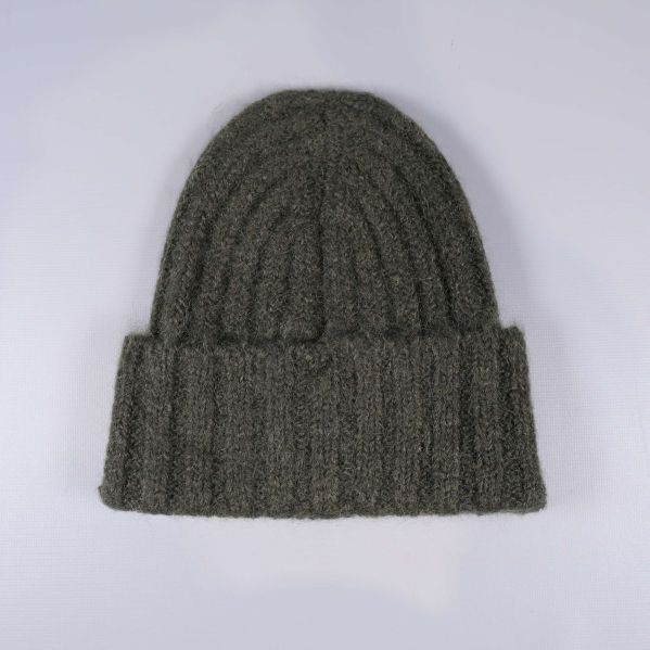 Grön mössa liggande med synlig stickad struktur