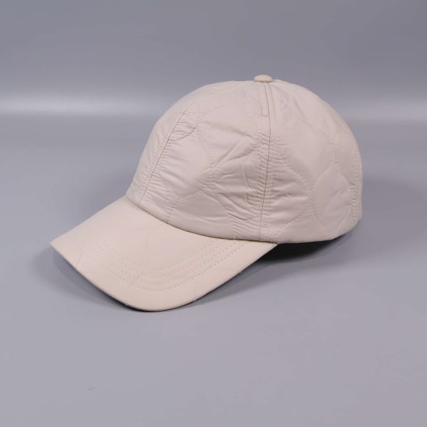 Beige quiltad keps i sidovy på grå bakgrund