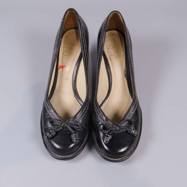 Överifrån av två svarta pumps med rosett framtill