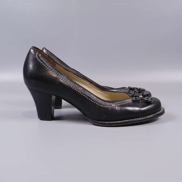 Profil av svarta pumps med klack och rosett framtill