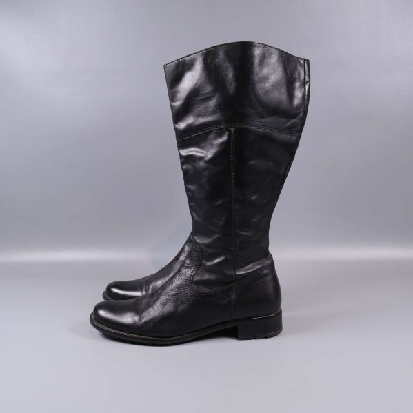 Höga svarta stövlar i profil mot grå bakgrund