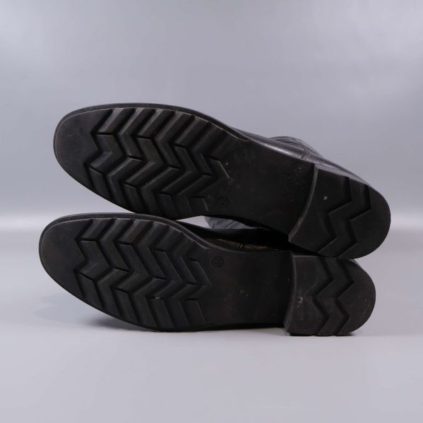 Stövlarnas svarta mönstrade sulor synliga underifrån