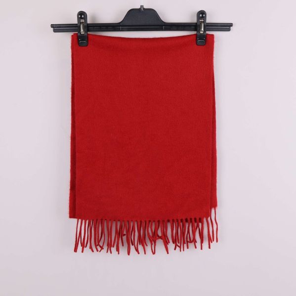 Röd halsduk med fransar hänger utsträckt på galge
