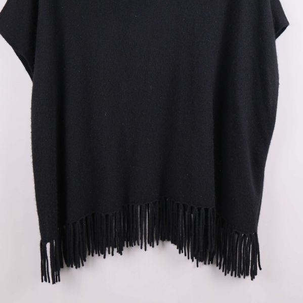 Närbild på svart poncho med fransad nederdel