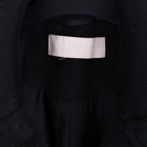 Närbild på etikett med Keepsake-logotyp i svart kappa