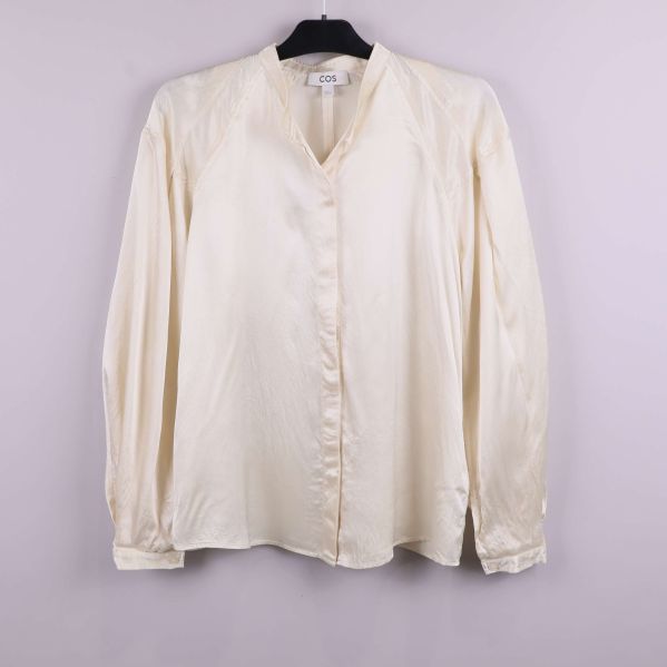 Ljus blus med lång ärm framifrån på galge