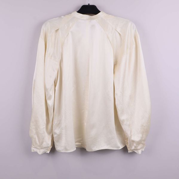 Ljus blus med lång ärm bakifrån på galge