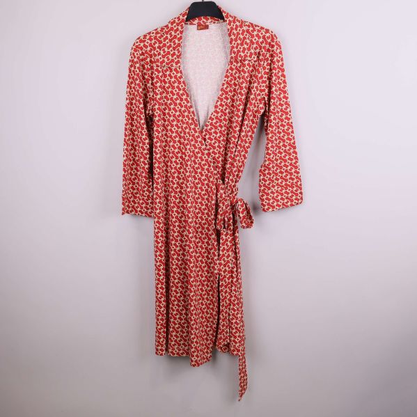 Lång röd omlottkimono med grafiskt mönster hängande mot vit bakgrund