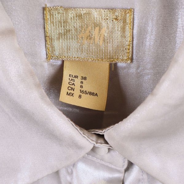 Guldfärgad H&M-etikett och storleksmärkning i kragen