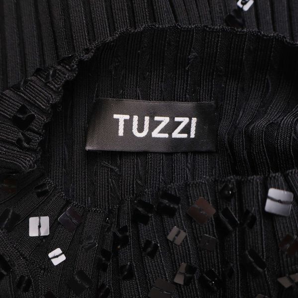 Närbild på Tuzzi logotyp på svart topp