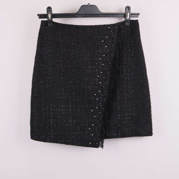 Framsida av svart tweedkjol med nitar och asymmetrisk kant