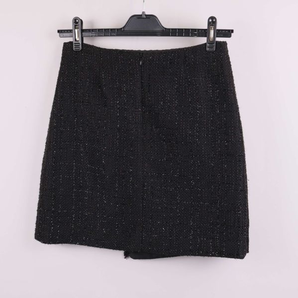 Baksida av svart fodrad tweedkjol på galge