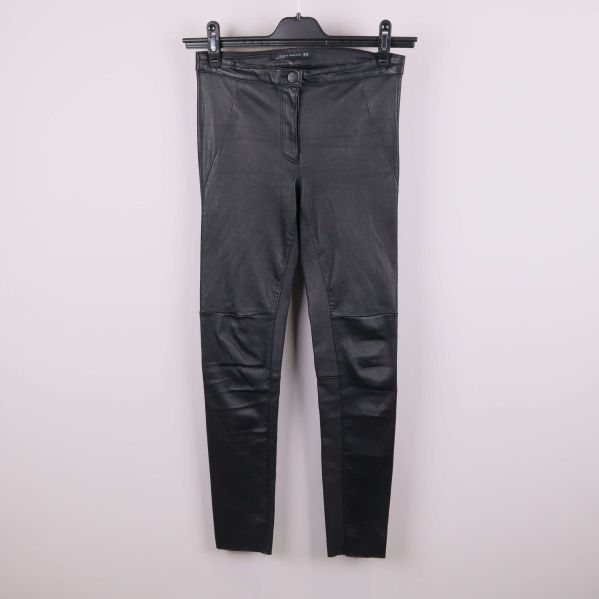 Framsida av svarta byxor med läderlook på galge