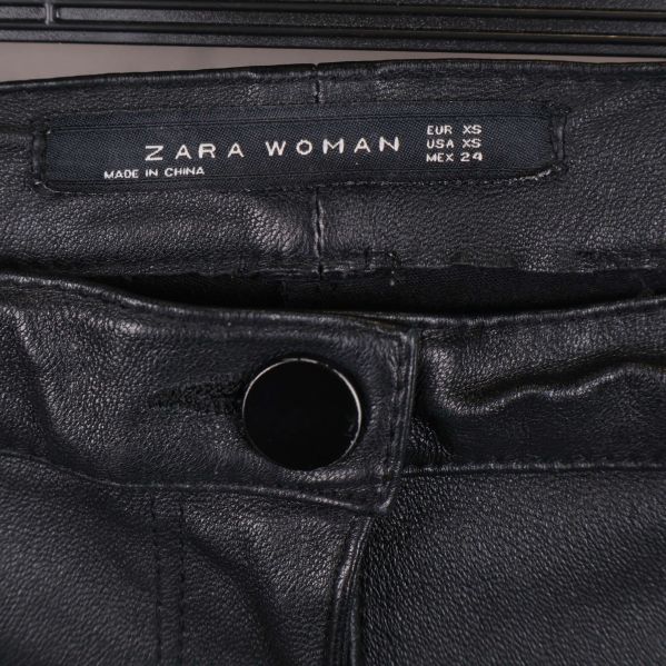 Närbild på midja med ZARA WOMAN etikett och knapp