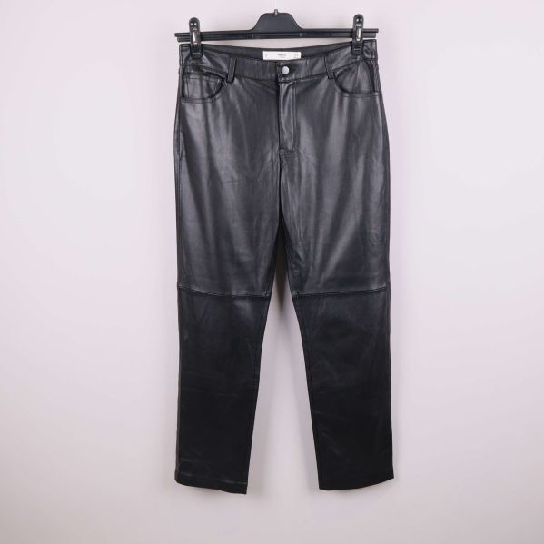 Svarta byxor i konstläder fotograferade framifrån på galge