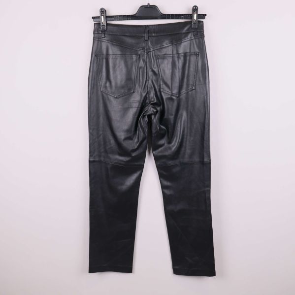 Svarta byxor i konstläder fotograferade bakifrån på galge