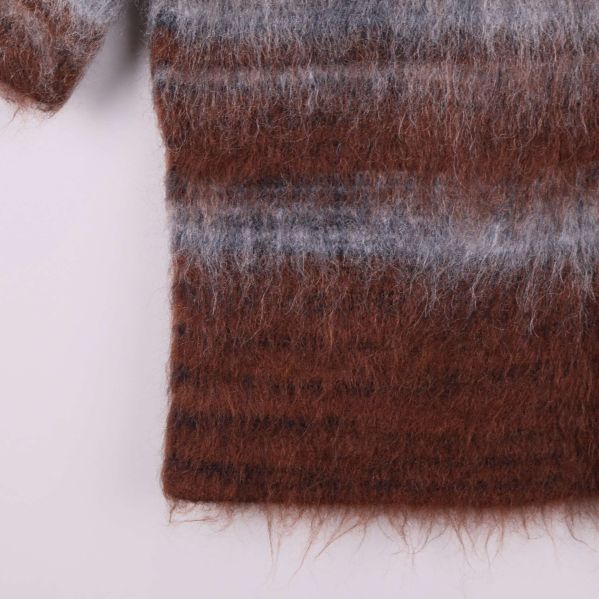 Nederkant på brun och grå randig stickad topp visas nära