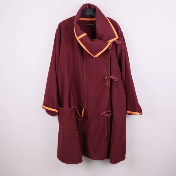 Vinröd ulljacka med orange kantband framifrån på galge