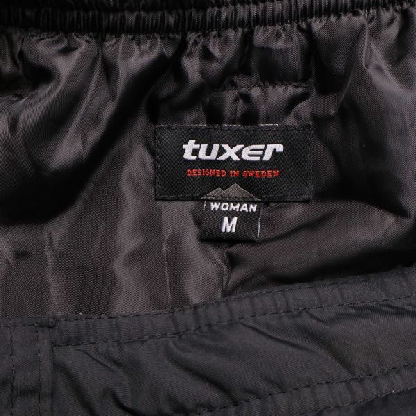 Närbild på tuxer logotyp och M-storleksetikett inuti kjolen