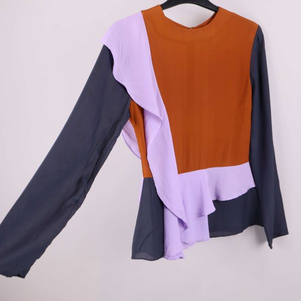 Blus visad från sidan med asymmetrisk volang