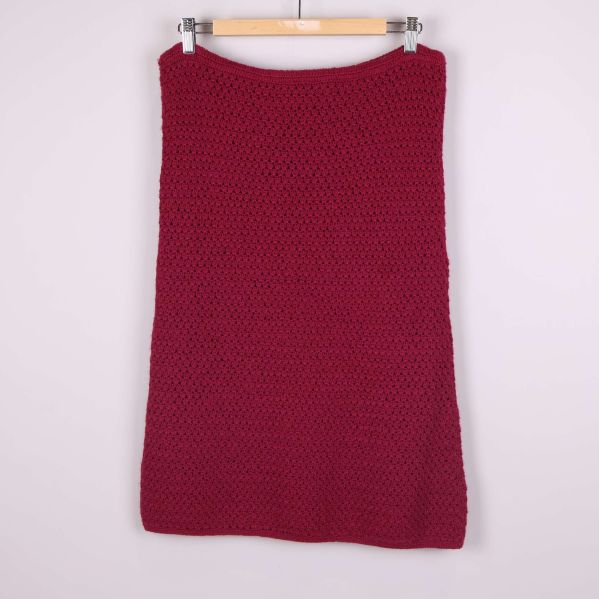 Stickad mörkröd kjol sedd bakifrån mot ljus bakgrund