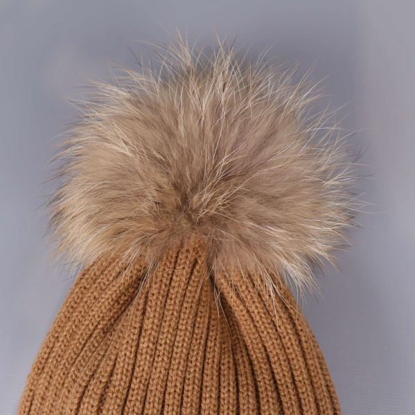 Närbild av beige mössans stora tofs upptill