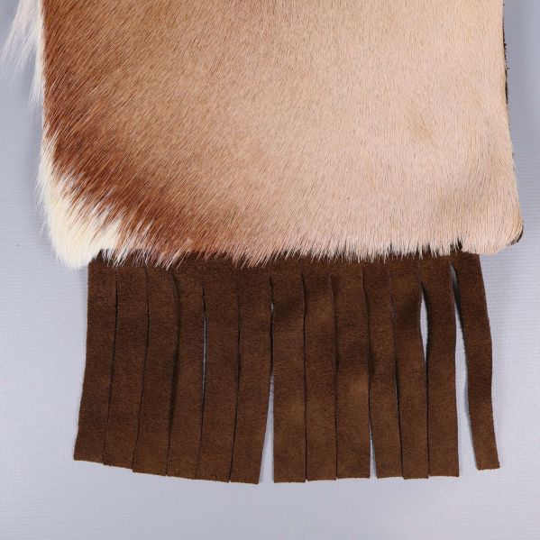 Närbild på bruna mockafransar längst ned på väskan