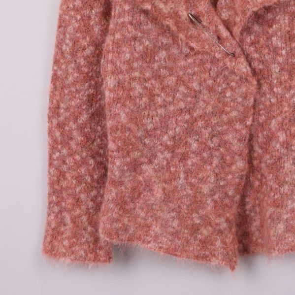 Stickad ärm och nederkant på aprikos jacka i närbild