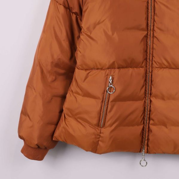 Närbild på fickor och dragkedjor med ringar på brun jacka