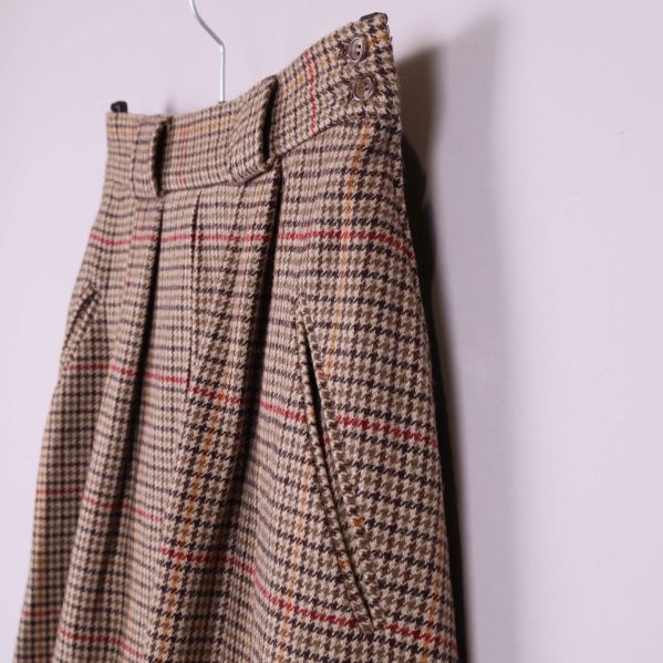 Närbild på fickor och midjedetaljer på rutigt tyg