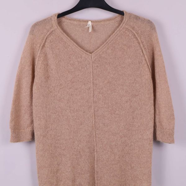 Närbild på överdelen och halsringning på beige stickad topp