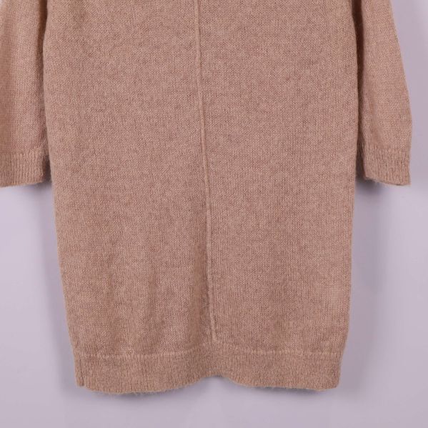 Närbild på nederkanten av beige stickad topp