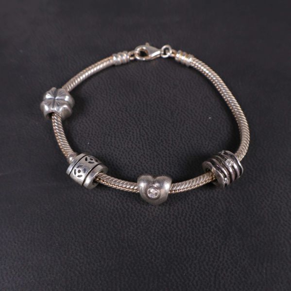 Närbild på armbandslänk med fyra olika berlocker