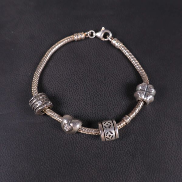 Armbandslänk i silverfärg med stängd lås och berlocker