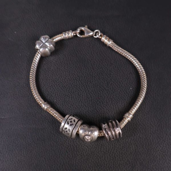 Armbandslänk liggande plant med berlocker synliga