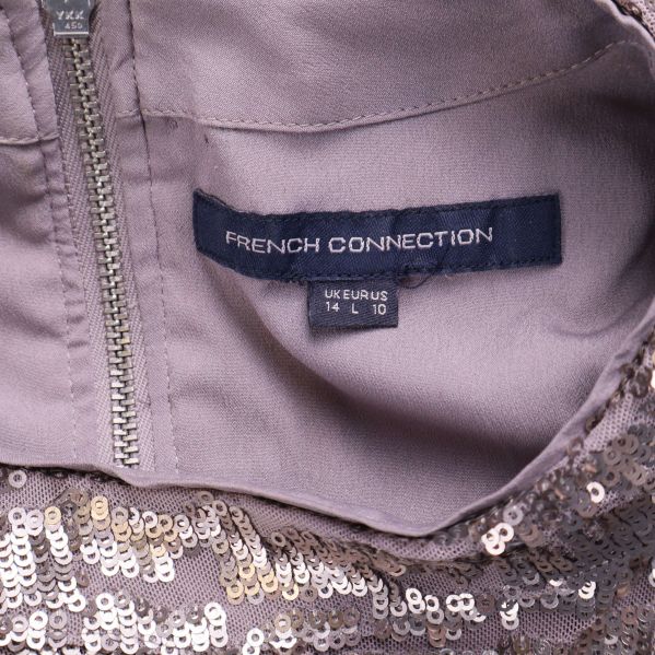 Närbild på French Connection-etikett och storleksmärkning i nacken på paljettopp