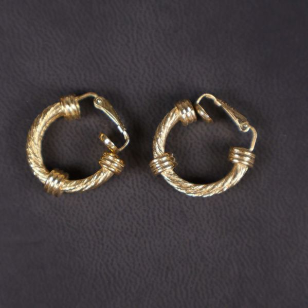 Två guldfärgade runda örhängen med tvinnad yta