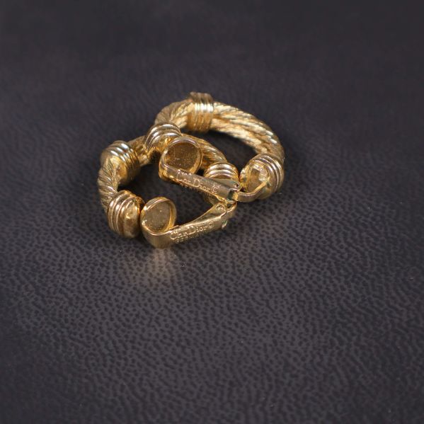 Guldfärgade örhängen liggande mot mörk bakgrund