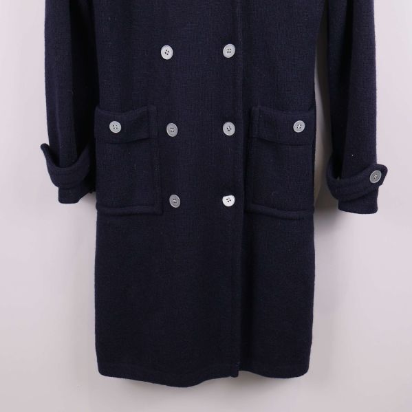 Närbild på kappa med fickor och knappar nertill