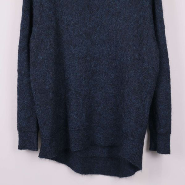 Närbild på nederkant och muddar av blå stickad tröja